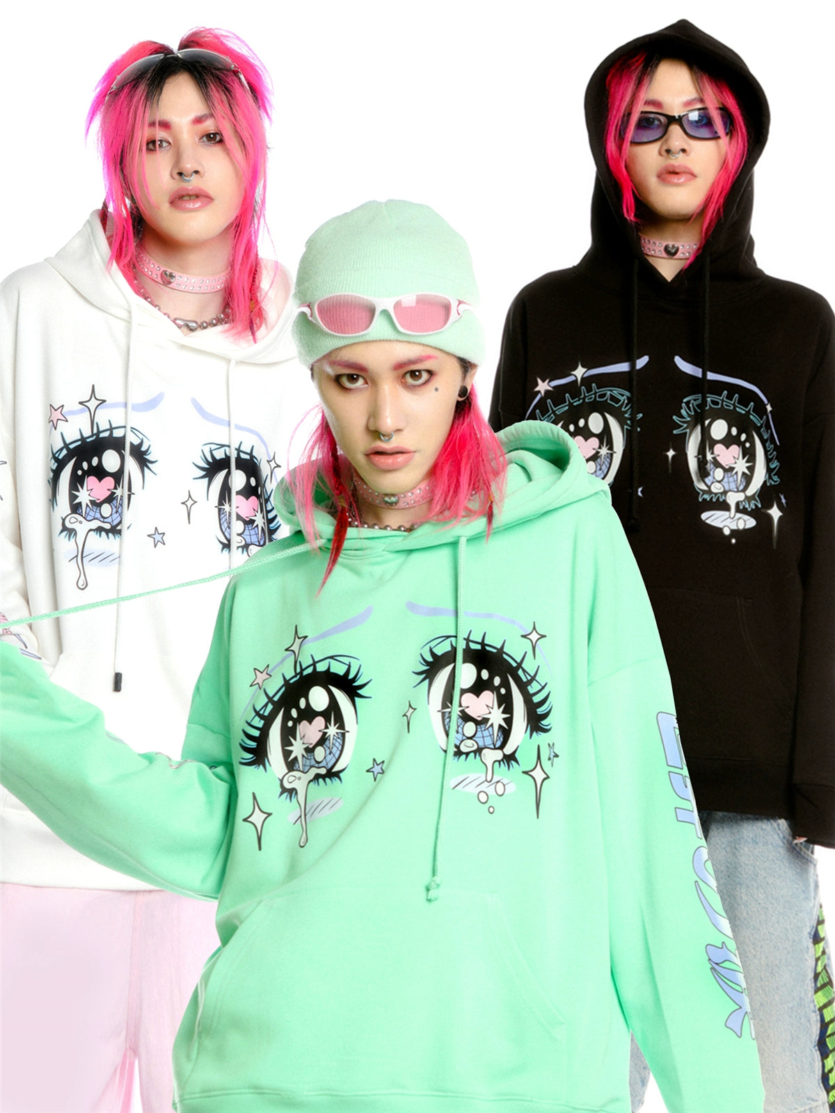 Three people dressed in vibrant Seakoff anime-style hoodies featuring the Kawaii Aesthetic Crying Eyes design. One wears a mint green beanie and sunglasses, another a white hoodie, and the third a black one. All have pink hair, perfectly embodying kawaii fashion against a white background.