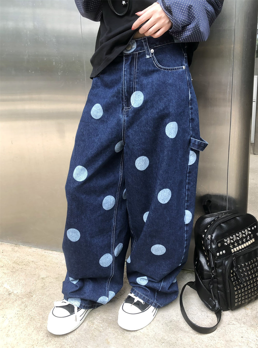 Model wearing dark wash baggy jeans with light blue polka dots, front view