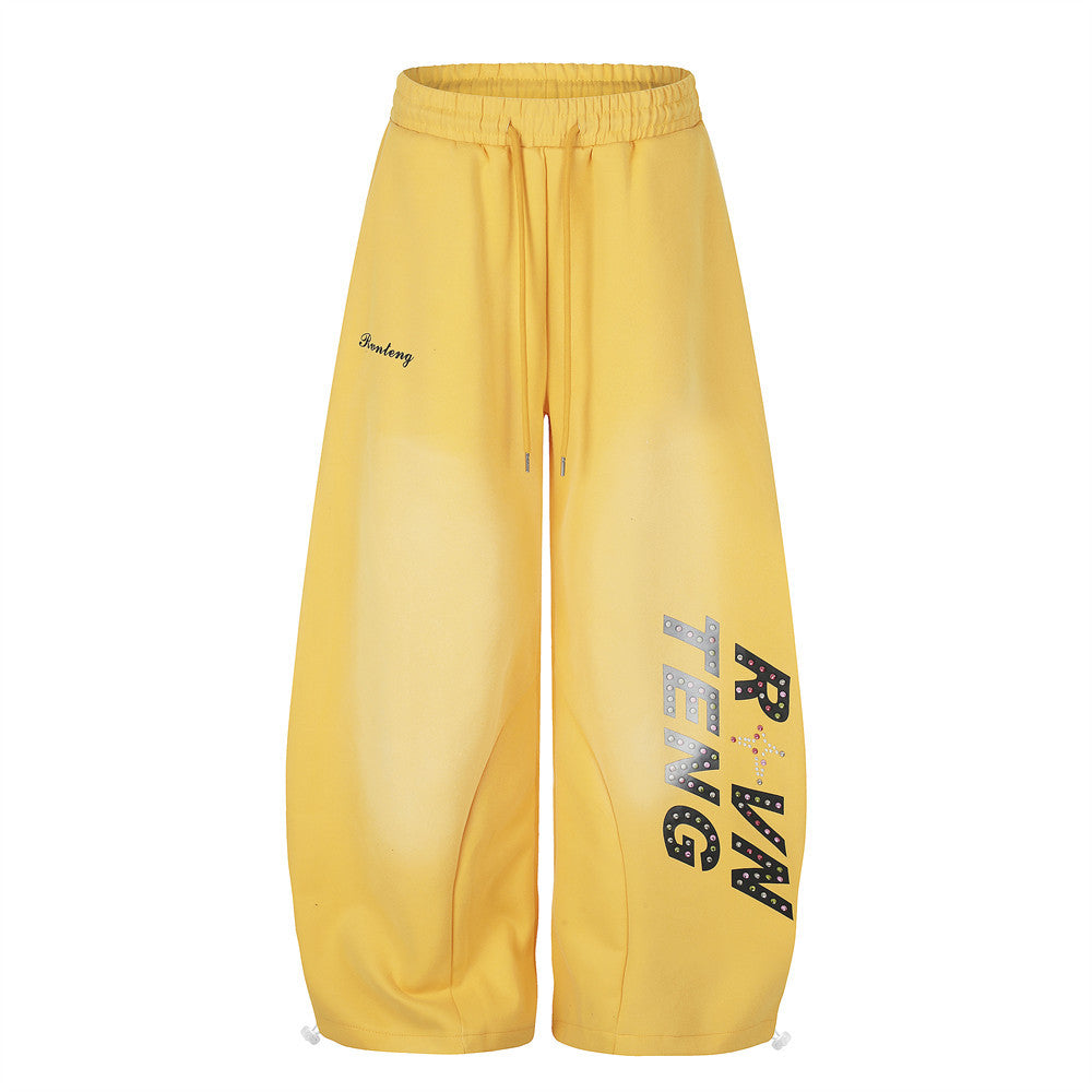 Yellow wide leg sweatpants with rhinestone letter print on the leg, front view