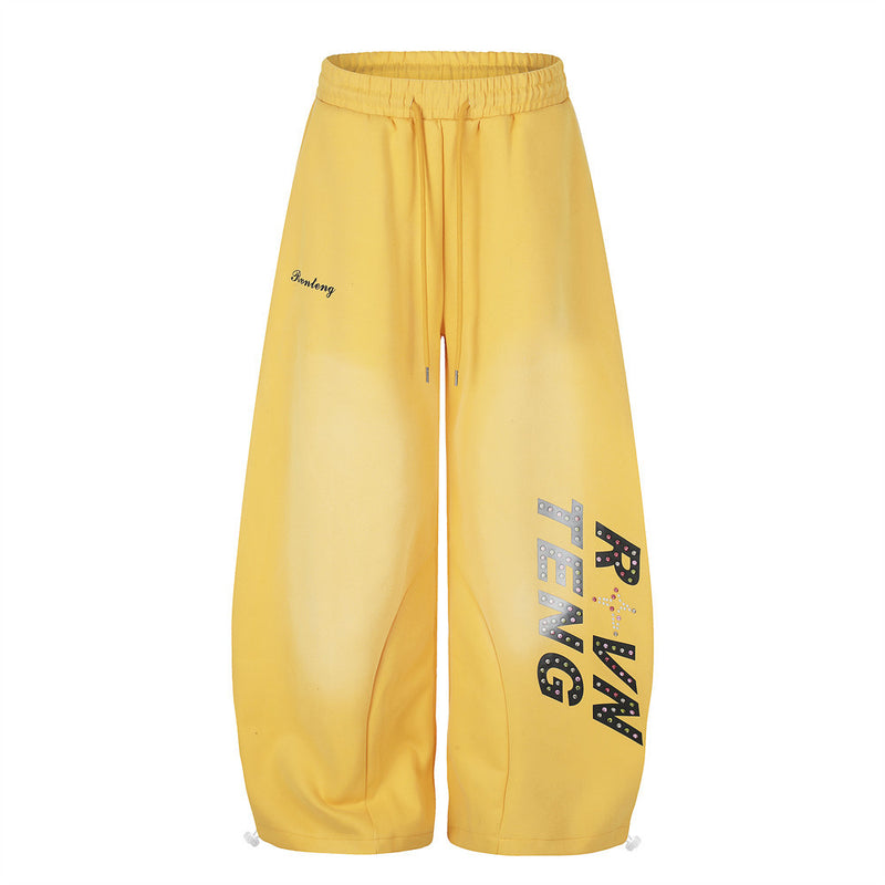 Yellow wide leg sweatpants with rhinestone letter print on the leg, front view