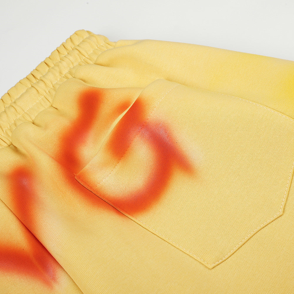 Close-up of yellow sweatpants back pocket with orange spray-dye detail