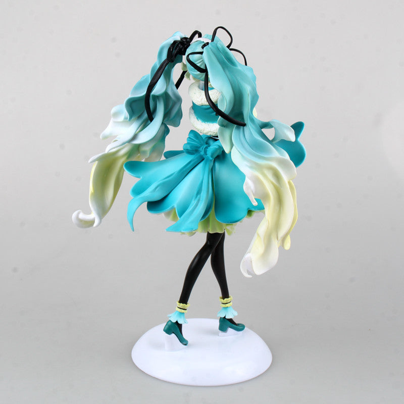 The Hatsune Miku 1/7 Scale 28cm PVC Figure showcases an anime character with flowing blue and white hair in a blue dress with ribbons. She stands gracefully on a white base, wearing blue heeled shoes that embody the Vocaloid collectible charm.