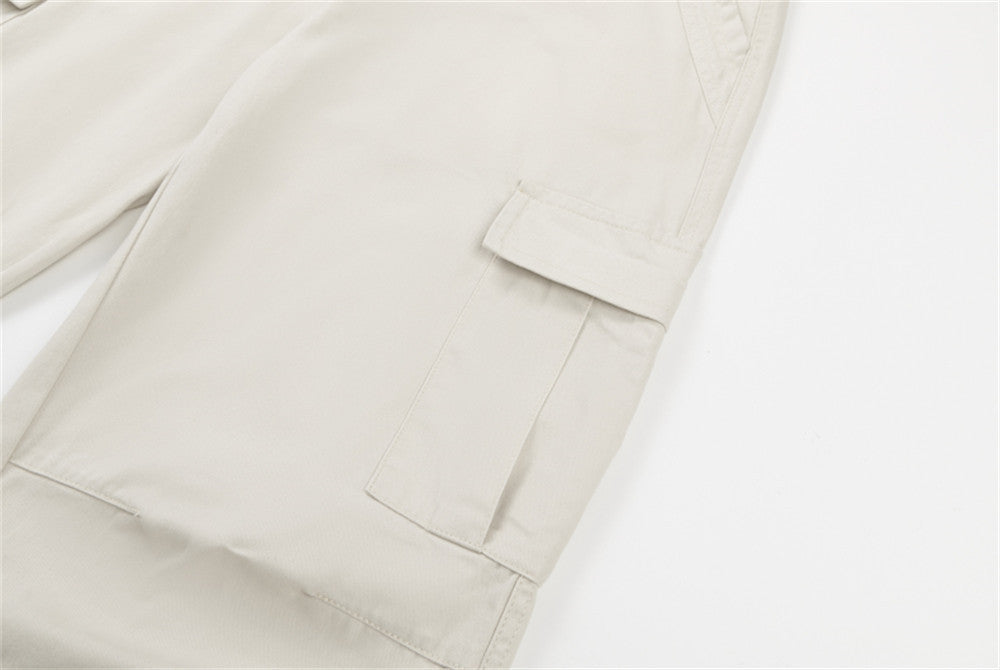 Close-up of cream cargo pants side flap pocket and hem seam
