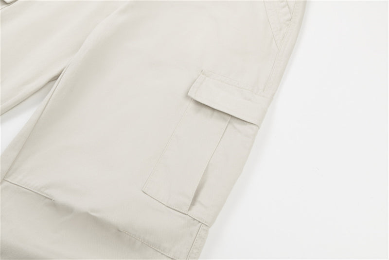 Close-up of cream cargo pants side flap pocket and hem seam
