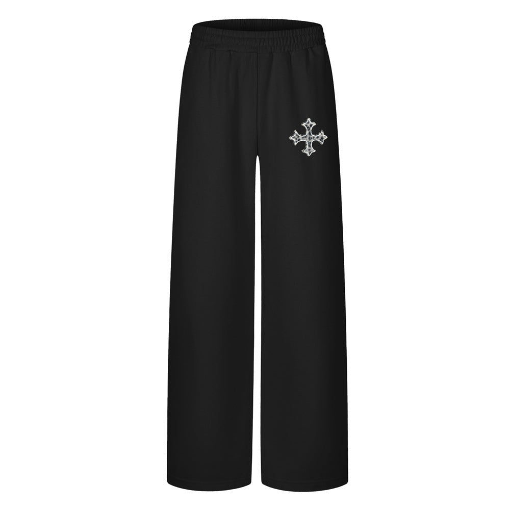 Wide-leg sweatpants with cross graphic print on left thigh, shown in black and light grey colorways