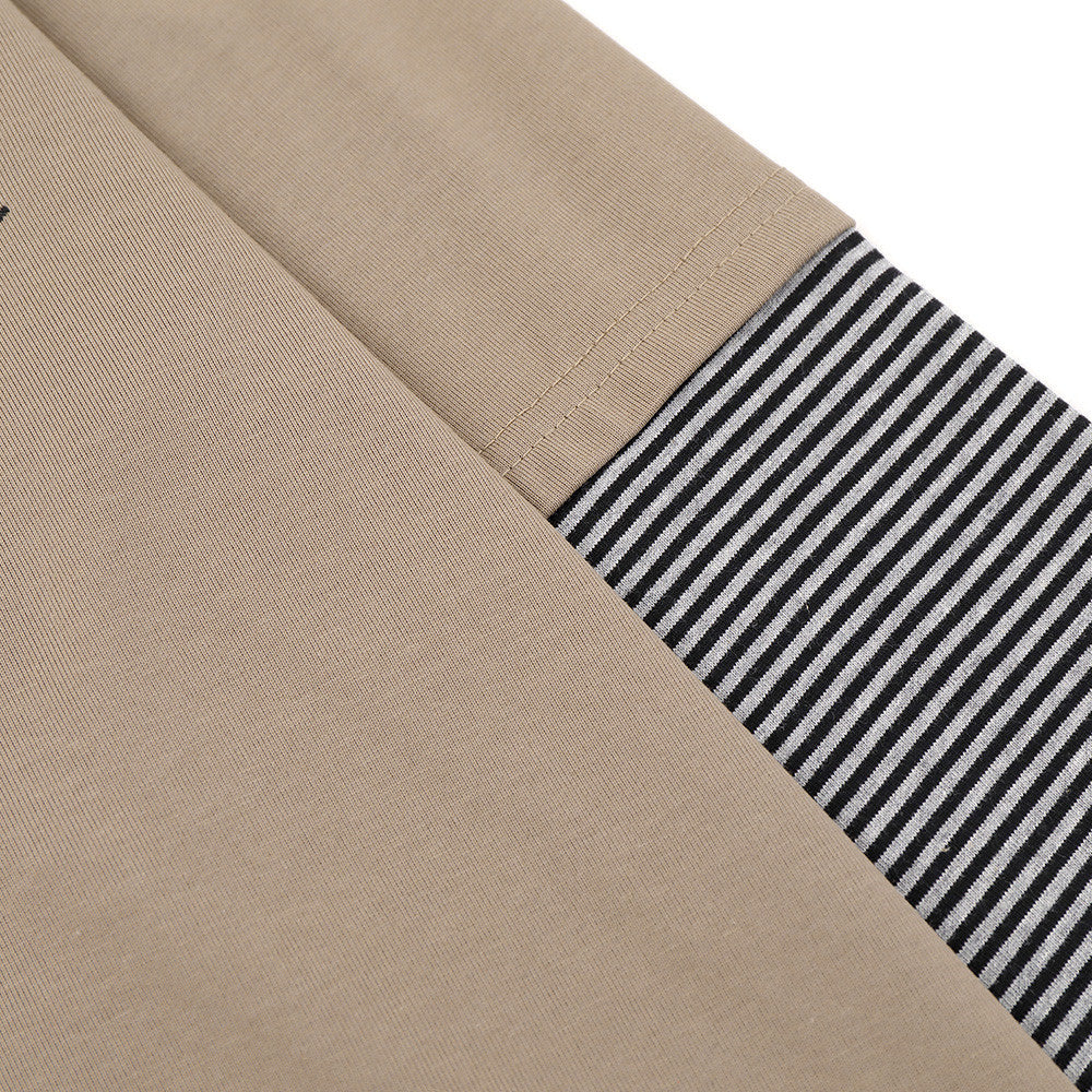 Close-up of khaki sleeve with black-and-white striped cuff and seam detail
