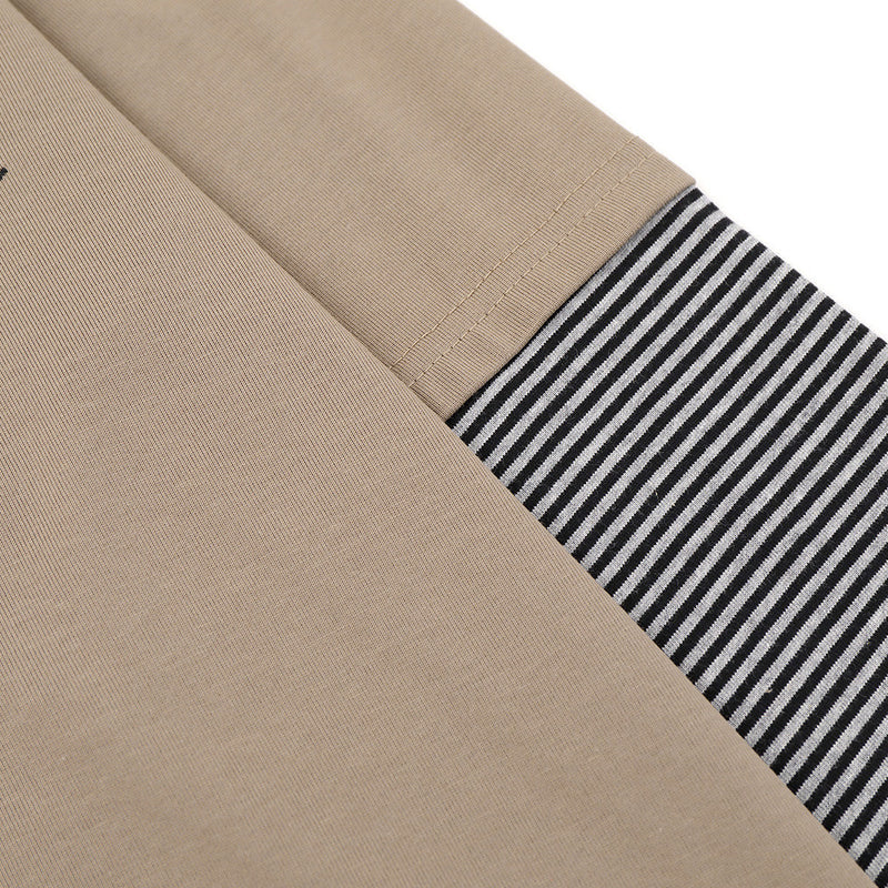 Close-up of khaki sleeve with black-and-white striped cuff and seam detail
