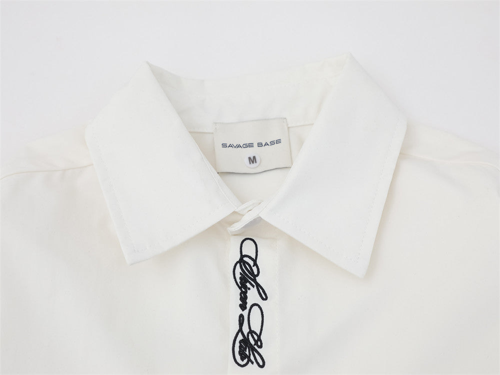 Close-up of white shirt collar and top placket with script embroidery and brand label