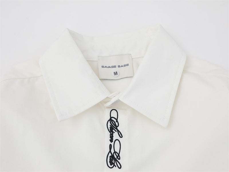 Close-up of white shirt collar and top placket with script embroidery and brand label