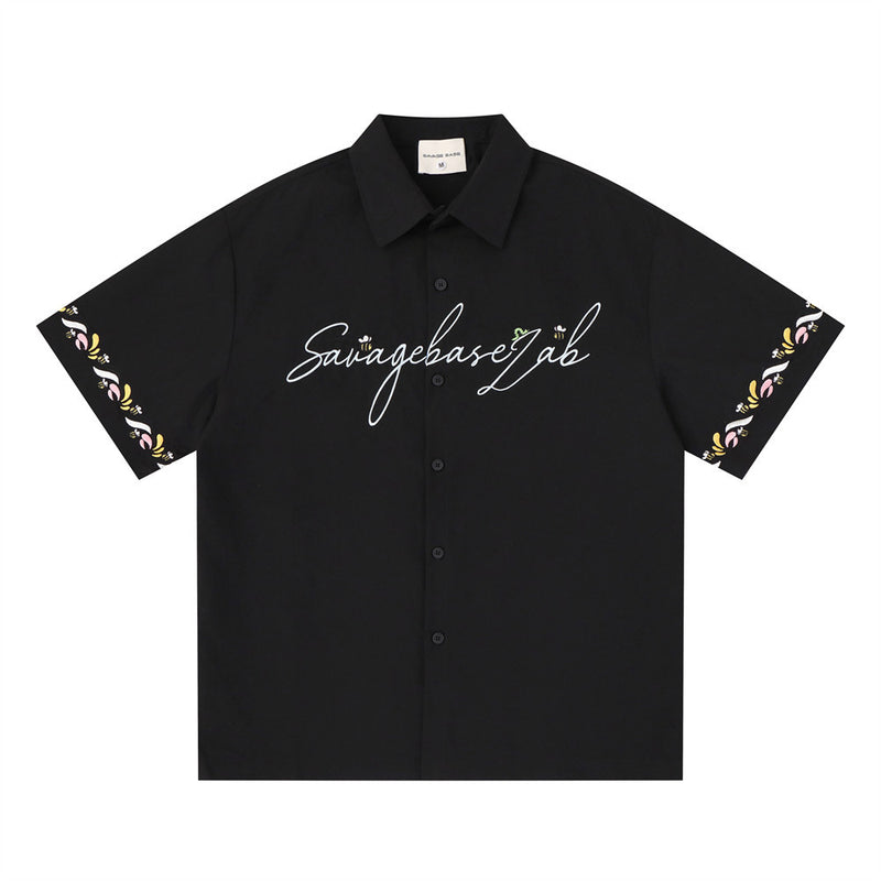 Men's oversized short sleeve button-up shirt in black with cursive Savagebase Lab chest logo and floral embroidery sleeve tri
