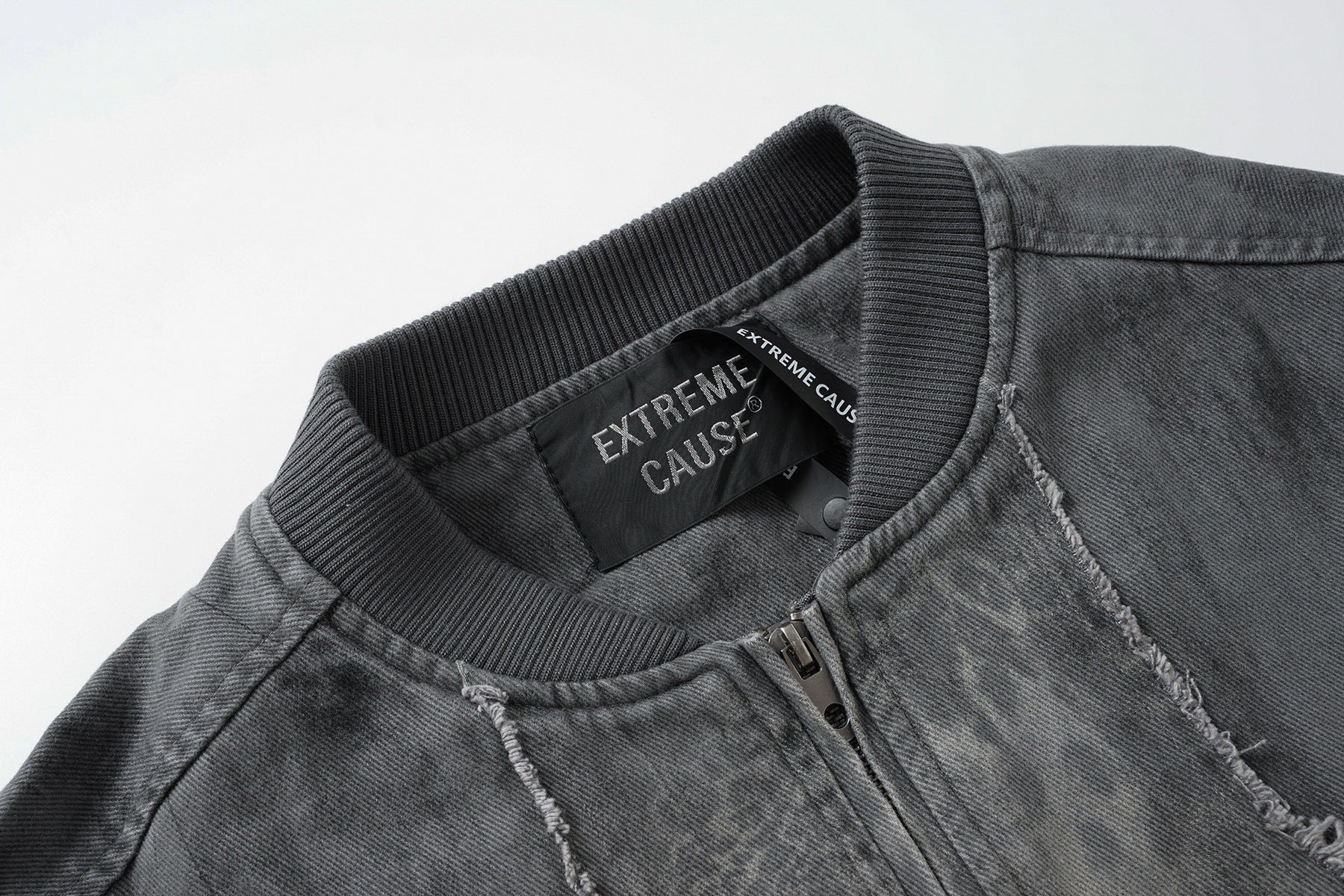 Veste bomber en jean délavé déconstruite à empiècement croisé et coutures effilochées