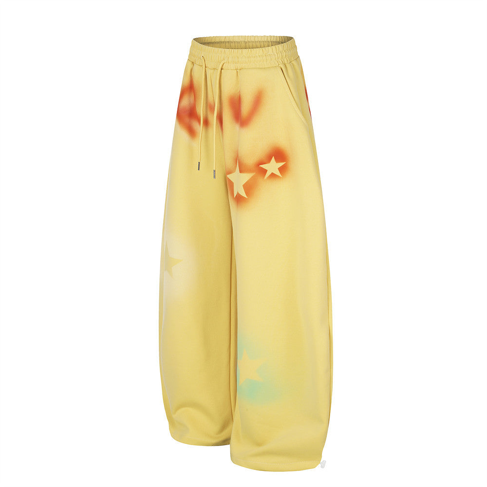 Yellow wide leg sweatpants with star graffiti spray-dye shown angled front view