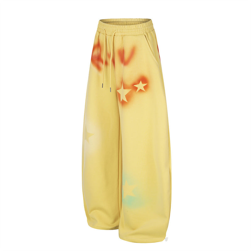 Yellow wide leg sweatpants with star graffiti spray-dye shown angled front view