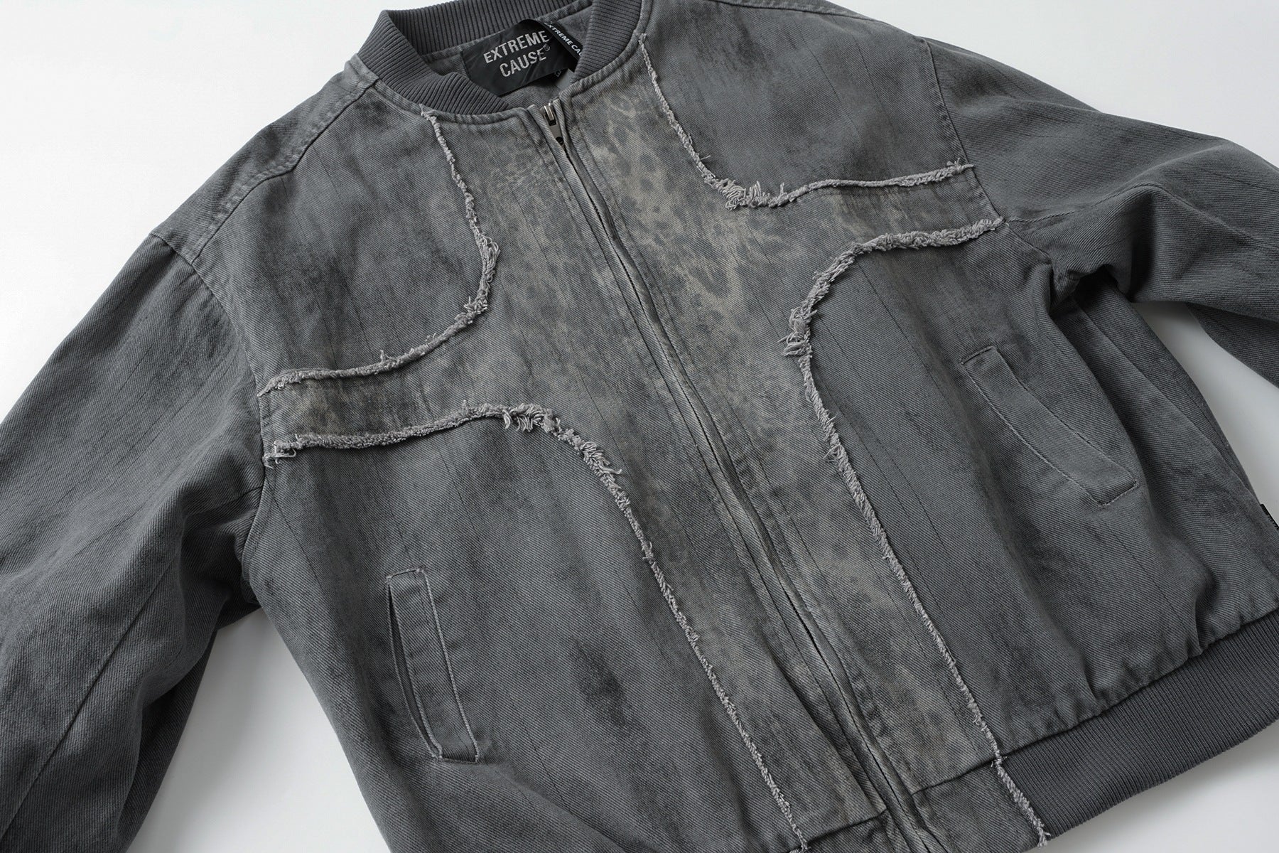 Veste bomber en jean délavé déconstruite à empiècement croisé et coutures effilochées