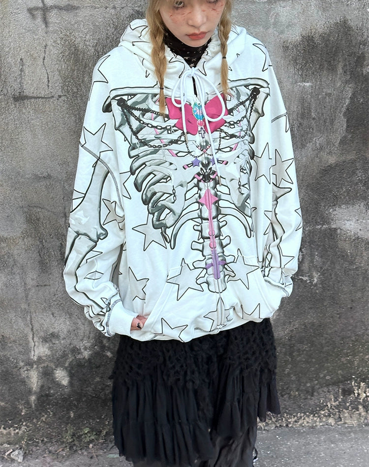 A person in a Seakoff Gothic Skeleton Star Hoodie, showcasing a skeleton print and star pattern, stands against a textured wall. The white full-zip hoodie with a pink heart graphic pairs perfectly with their black lace skirt, capturing the essence of alternative fashion.