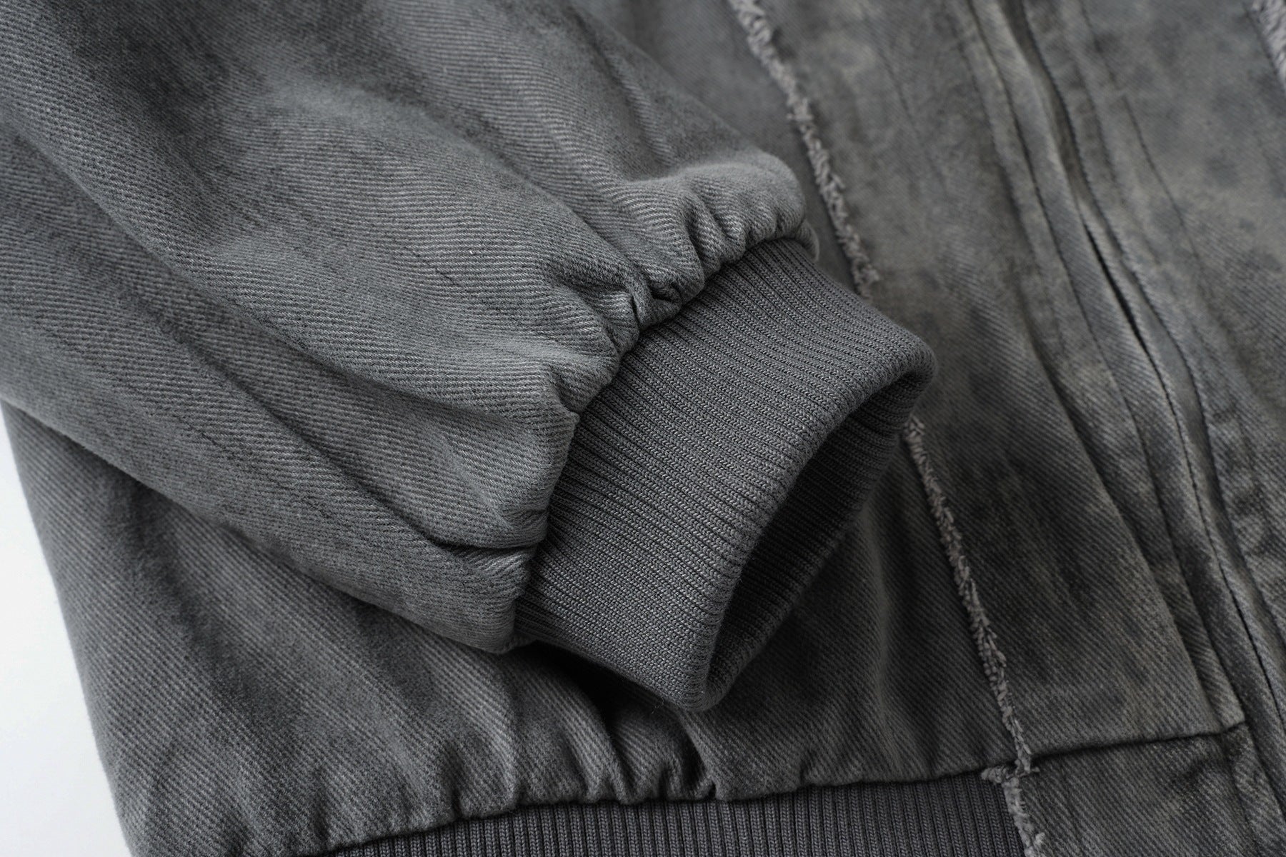 Veste bomber en jean délavé déconstruite à empiècement croisé et coutures effilochées