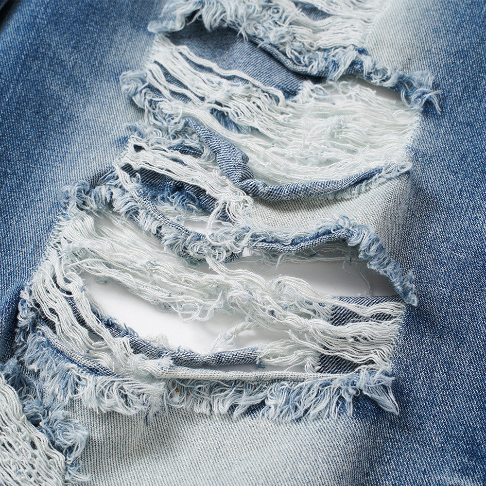 Close-up of frayed rip detail on light blue distressed denim