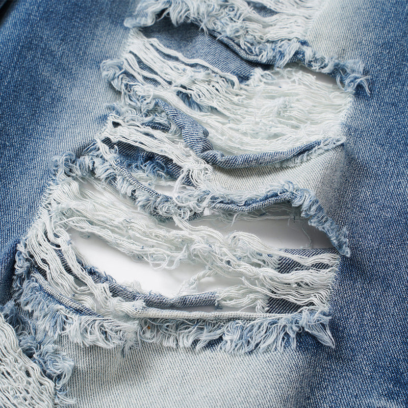 Close-up of frayed rip detail on light blue distressed denim