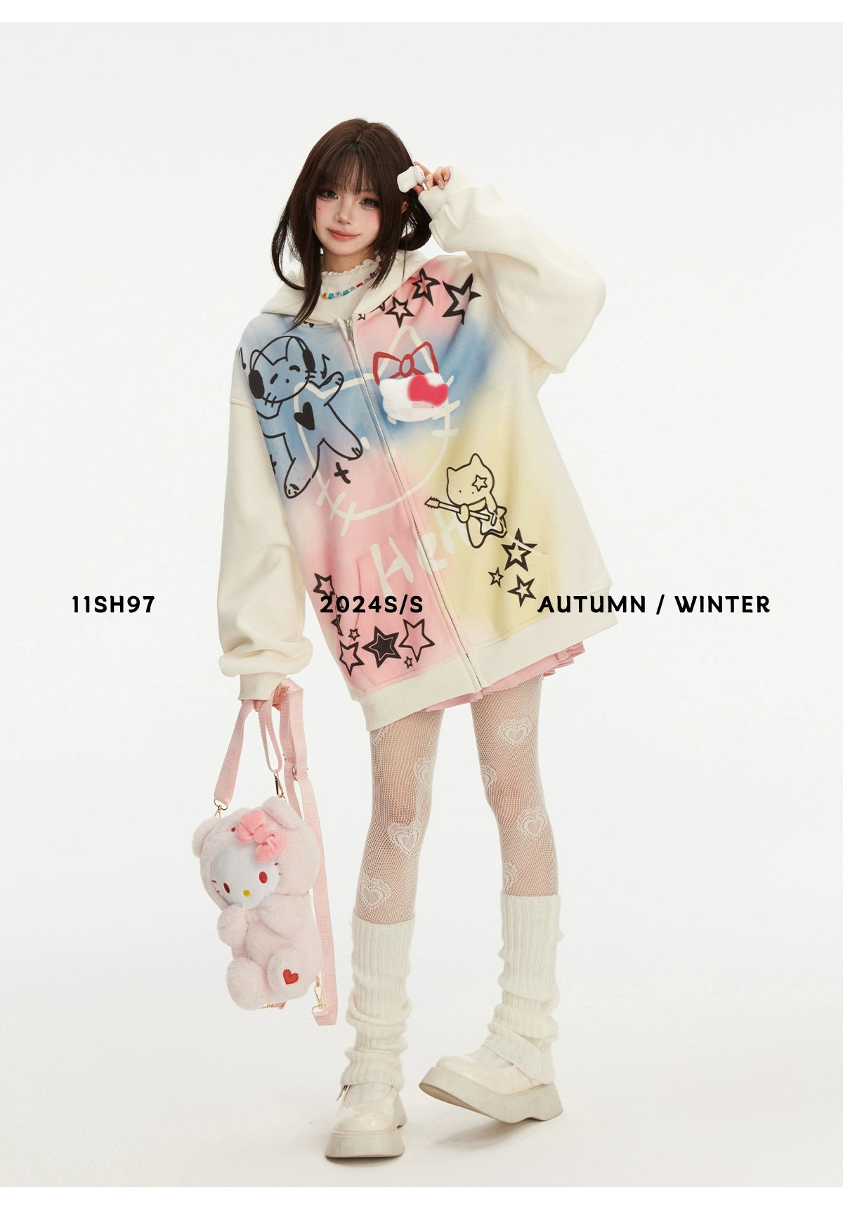 A model in a Pastel Cat Graffiti Hoodie by Seakoff holds a fluffy teddy bear purse, embracing kawaii fashion. She matches it with white patterned tights and chunky shoes against a plain backdrop. Text reads &quot;11SH97 2024 S/S AUTUMN / WINTER.