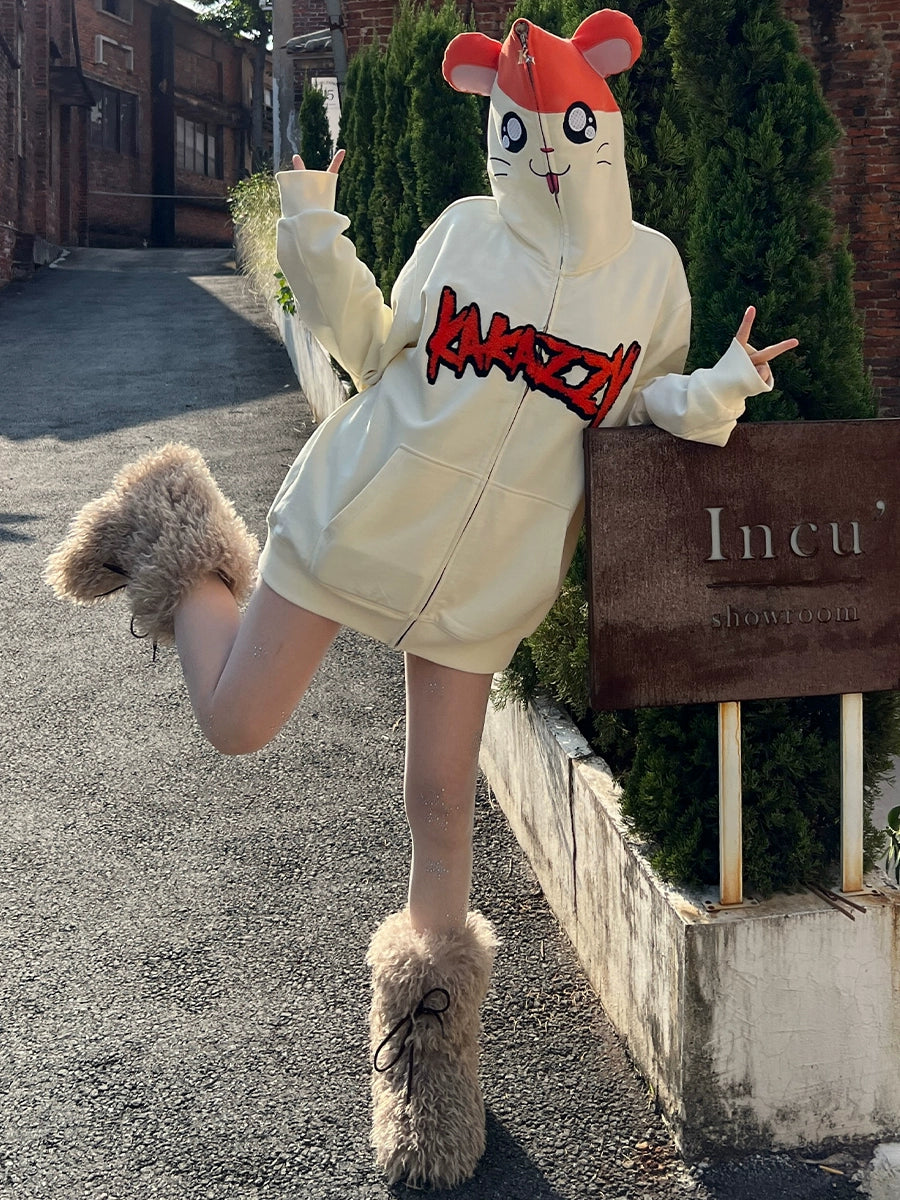 Wearing a Seakoff Cute Hamster Cartoon Hoodie with playful ear design and a red cap, a person strikes peace signs on one leg. Fluffy boots finish the look as they pose by a building, street, and trees—a charming scene for cartoon lovers&