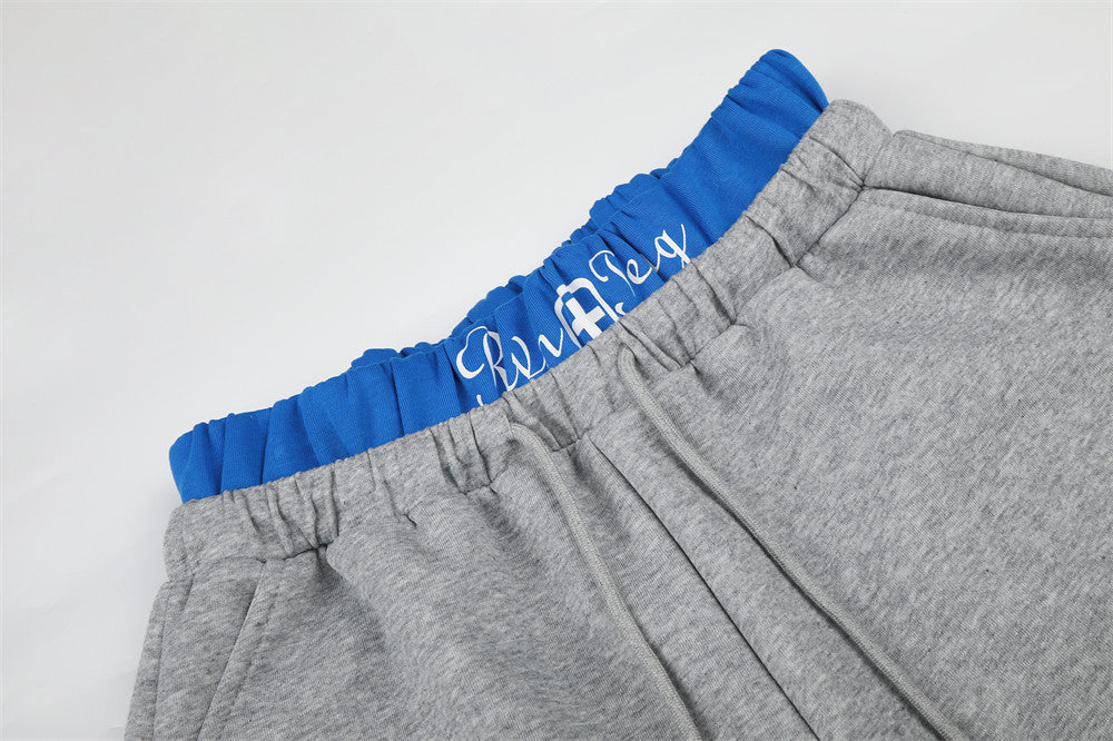 Close-up of gray sweatpants waistband with blue elastic band and white script detail