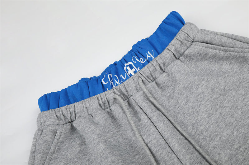 Close-up of gray sweatpants waistband with blue elastic band and white script detail