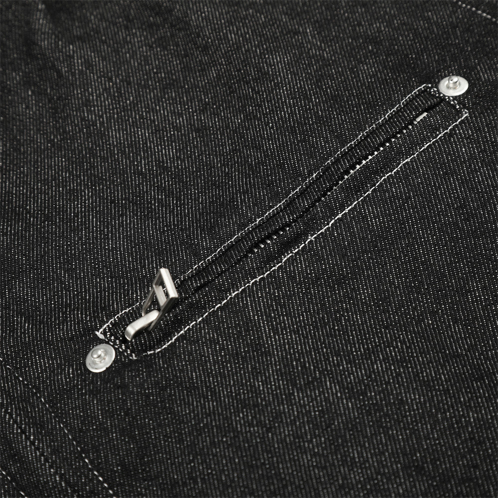 Close-up of black denim jacket chest zip pocket with silver zipper pull