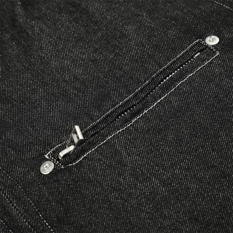 Close-up of black denim jacket chest zip pocket with silver zipper pull