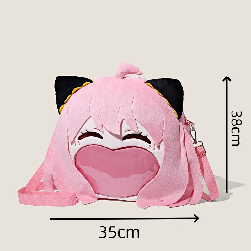 The Seakoff Spy x Family Anya Forger Plush Shoulder Bag is a pink anime-inspired design with black cat ears, closed eyes, and a big smile. Featuring a transparent mouth pocket and an adjustable strap, it measures approximately 38cm tall and 35cm wide.