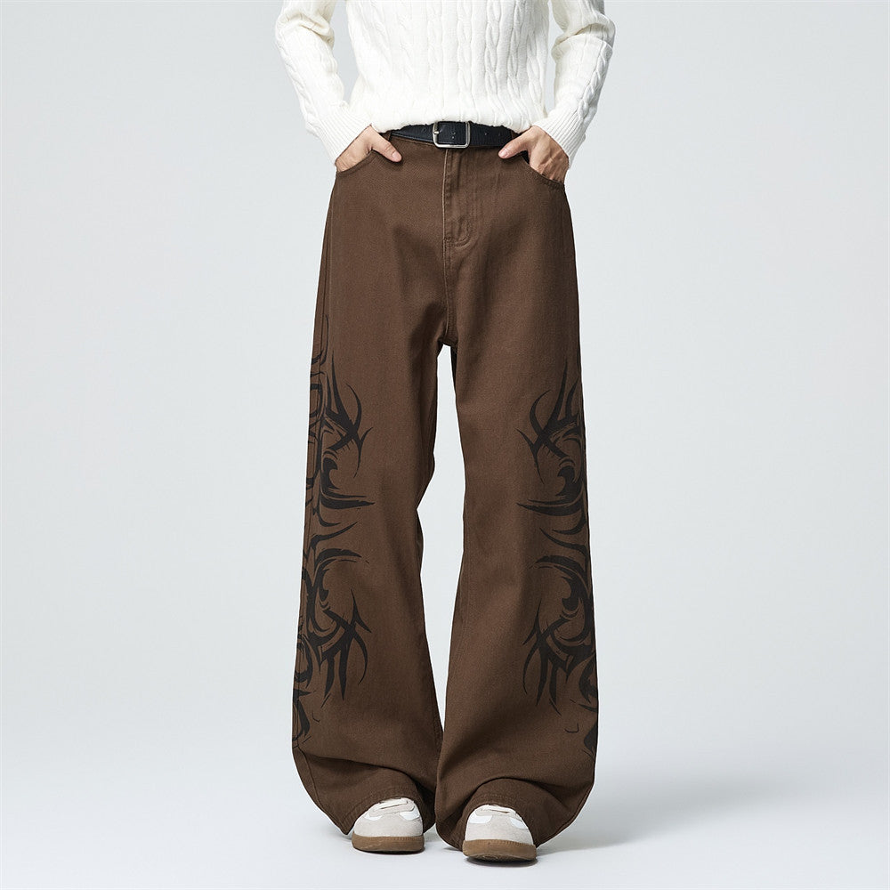 Men's wide-leg baggy jeans with tribal tattoo graphic print in brown colorway, styled with white knit sweater and sneakers