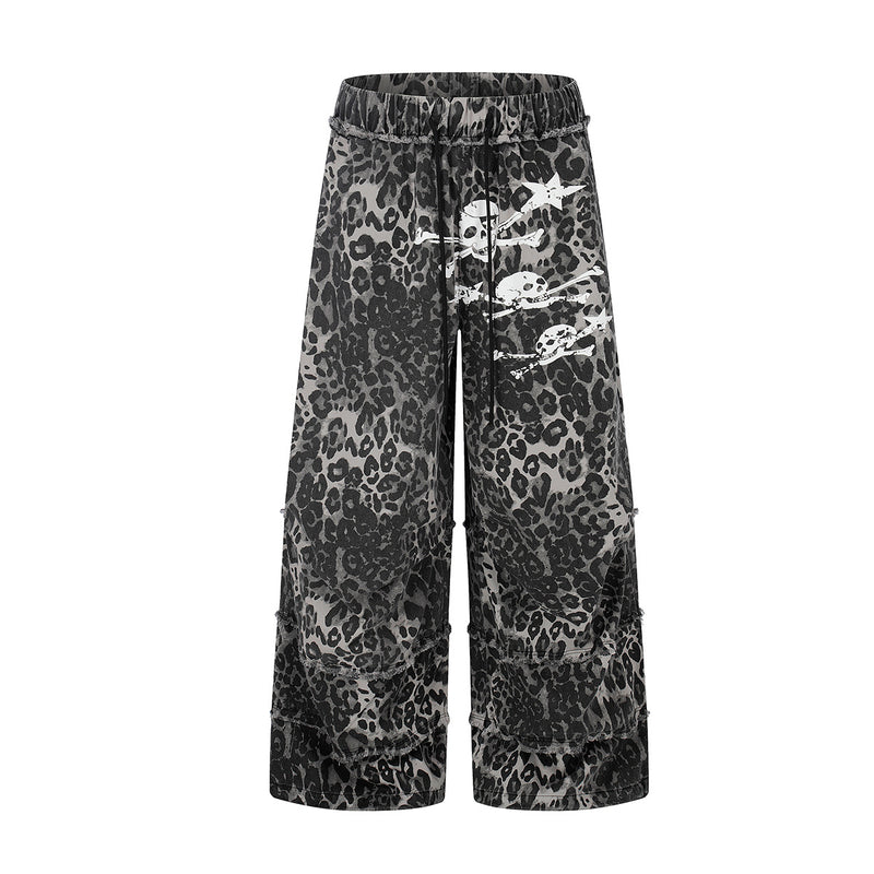 Grey leopard print wide-leg pants with white skull and crossbones graphic on front thigh and layered raw-edge hem