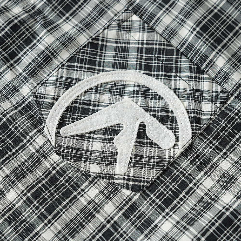 Close-up of embroidered chest pocket patch on black plaid shirt
