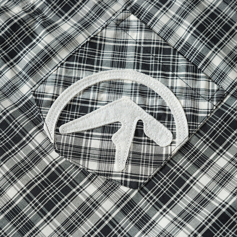 Close-up of embroidered chest pocket patch on black plaid shirt