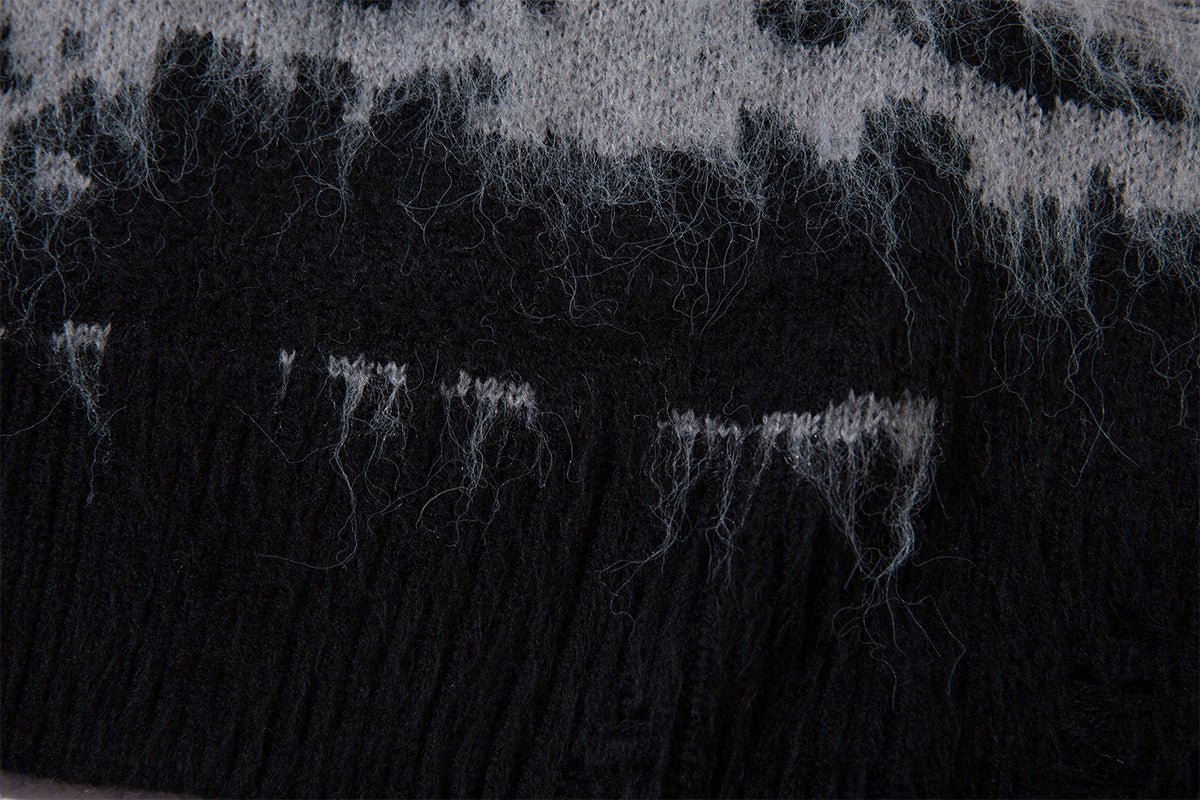 Close-up of the black ribbed hem with loose fuzzy fibers along the gray striped knit fabric