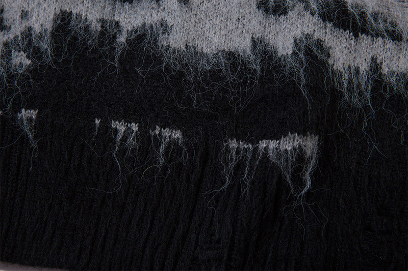 Close-up of the black ribbed hem with loose fuzzy fibers along the gray striped knit fabric