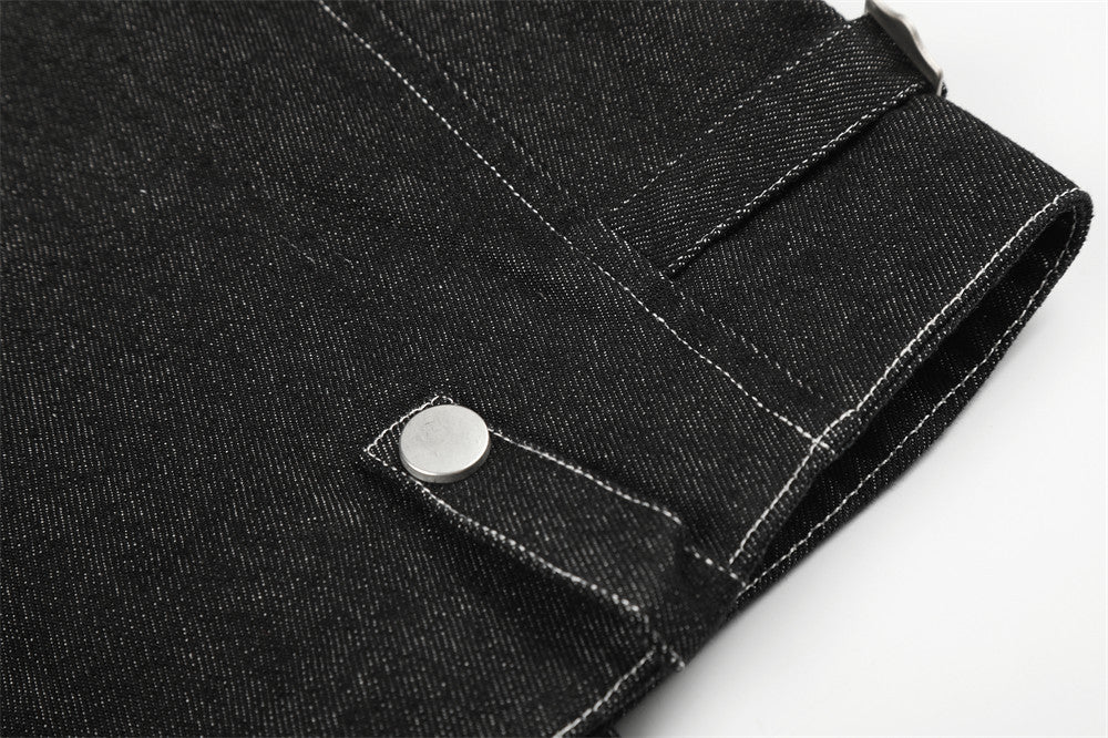 Close-up of black denim jacket lower hem with snap tab and straight stitching