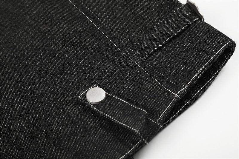 Close-up of black denim jacket lower hem with snap tab and straight stitching