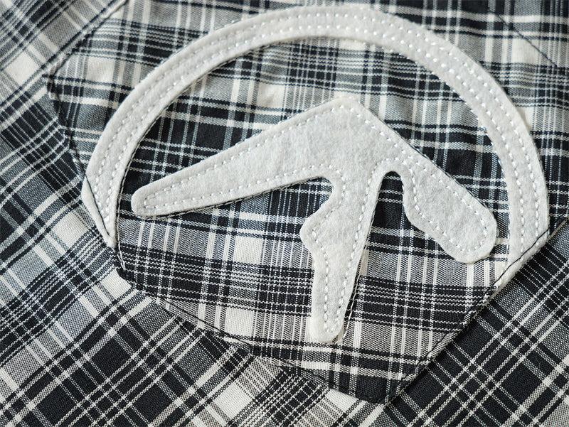 Close-up of embroidered chest pocket patch on light blue plaid shirt