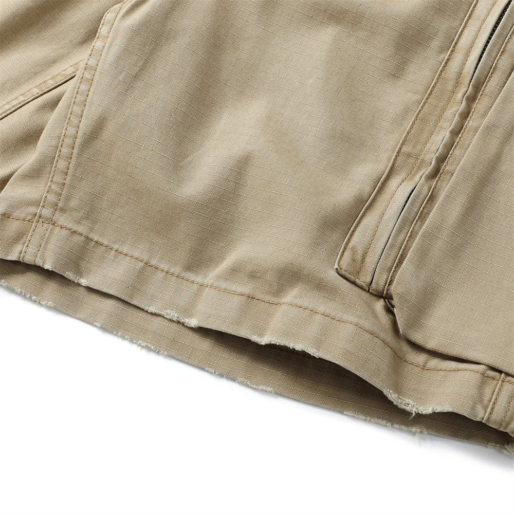 Close-up of khaki cargo shorts hem with frayed edge and side pocket seam