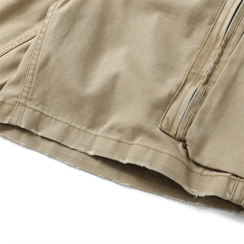 Close-up of khaki cargo shorts hem with frayed edge and side pocket seam
