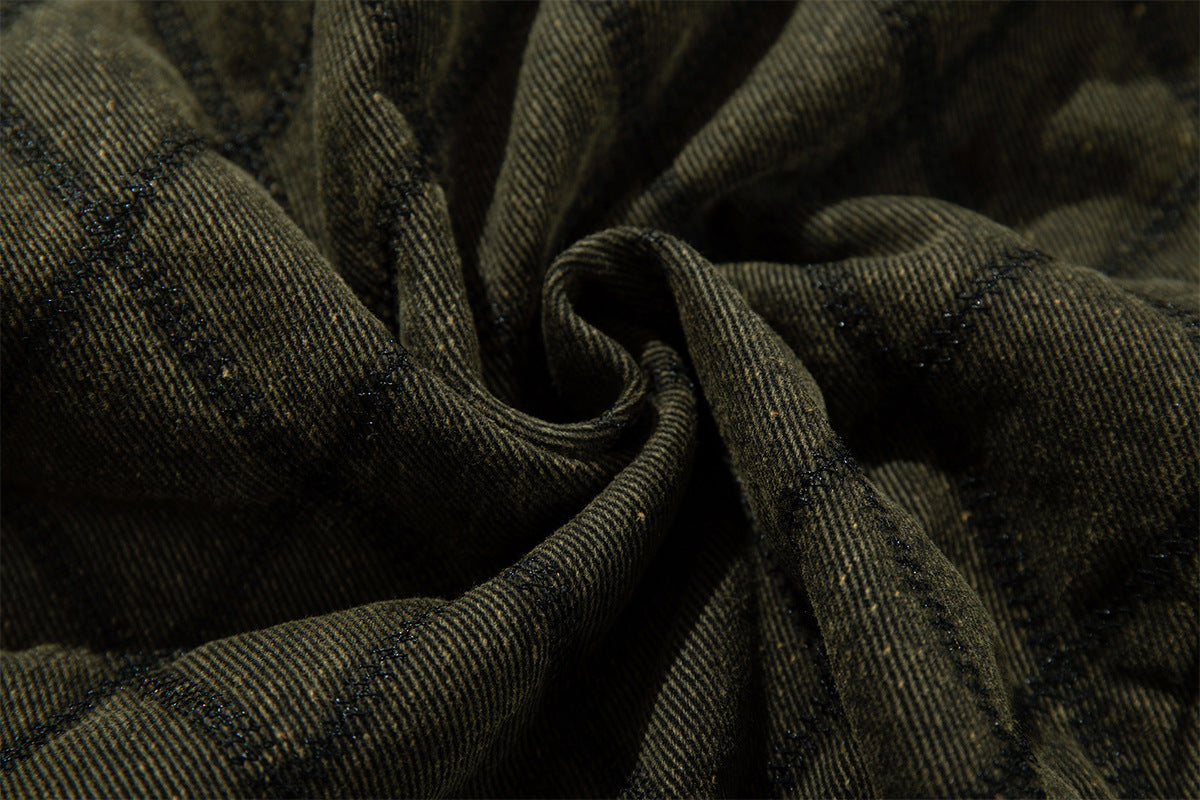 Close-up of olive green quilted jacket fabric gathered to show its textured weave and diamond stitching