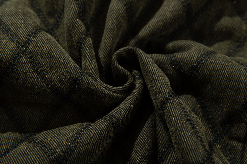 Close-up of olive green quilted jacket fabric gathered to show its textured weave and diamond stitching
