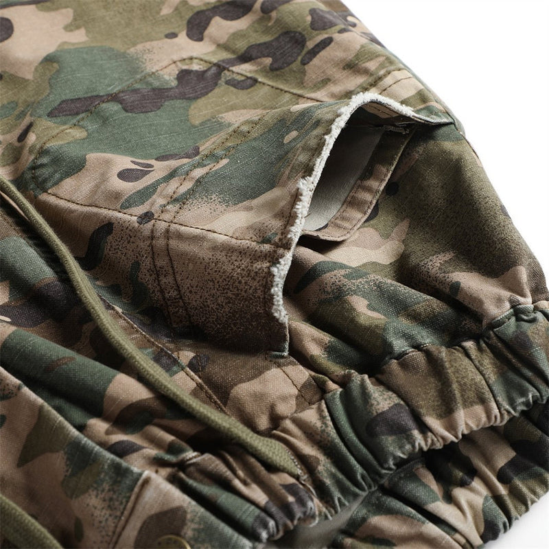 Close-up of camouflage shorts hem with frayed edge and stitched seam