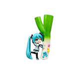 The Chibi Hatsune Miku Holding Green Onion 12cm PVC Figure features the character in a cute, playful Q-version, with long teal hair and a black and teal outfit, headphones on, posed beside a giant green onion while holding a microphone as musical notes dance around the vibrant leek.