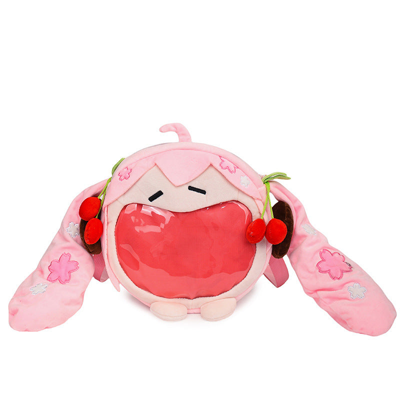 A charming Seakoff accessory, this round pink Hatsune Miku plush backpack has long ears with cherry and floral motifs. Its front features an ita bag-style transparent pocket and a small tuft on top, perfect for anime merch fans.