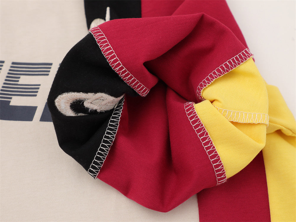 Close-up of sleeve cuff and stitched patch detail on red, black, and yellow fabric