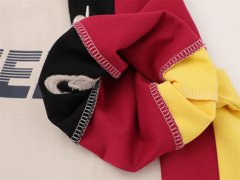 Close-up of sleeve cuff and stitched patch detail on red, black, and yellow fabric