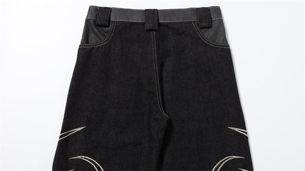 Back view close-up of black jeans seat and upper legs with partial embroidery
