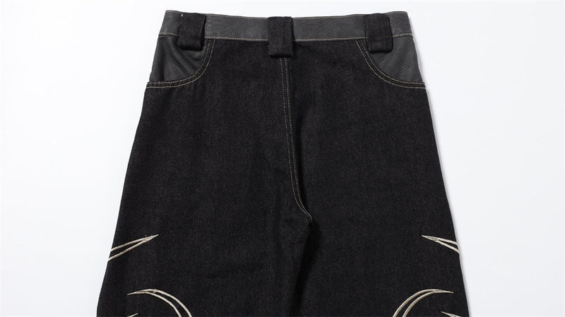 Back view close-up of black jeans seat and upper legs with partial embroidery