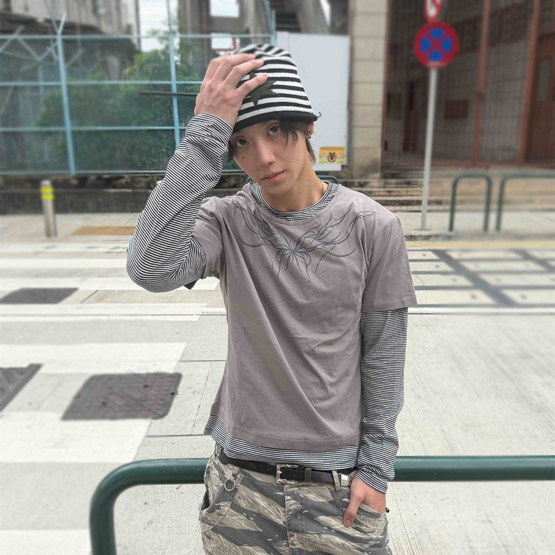 Men's faux two-piece striped long sleeve t-shirt with abstract tribal butterfly graphic print in gray, worn with camo pants